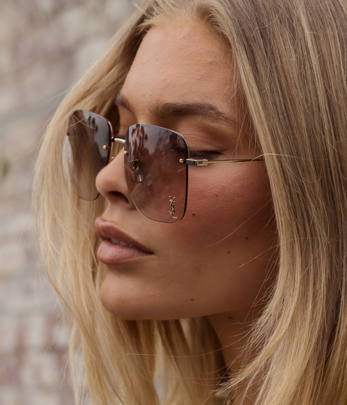 ALT text: Saint Laurent rimless sunglasses with gold frames, gradient-effect lenses, and Cassandre monogram