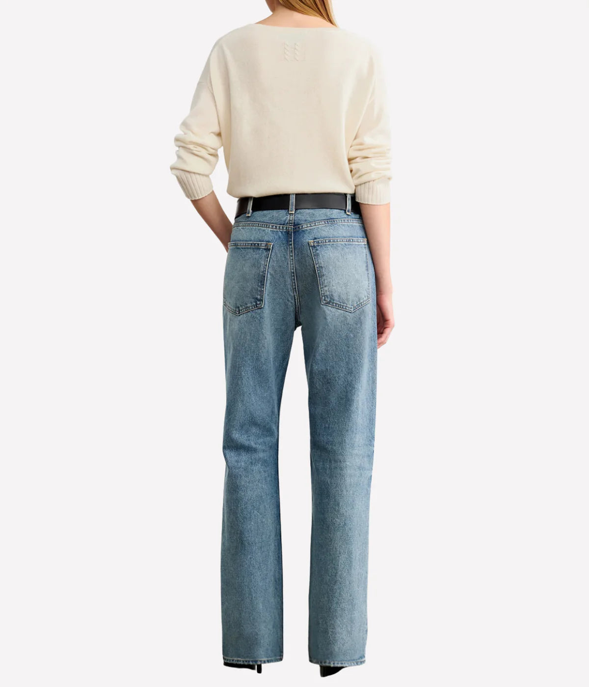 Person wearing a cream sweater and light blue jeans on a white background. Nili Lotan sweater