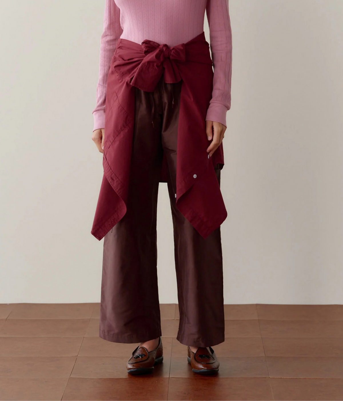 DONNI. Silk Taffeta Cargo Pant in Espresso styled on model with burgundy knit tied at the waist, front view.
