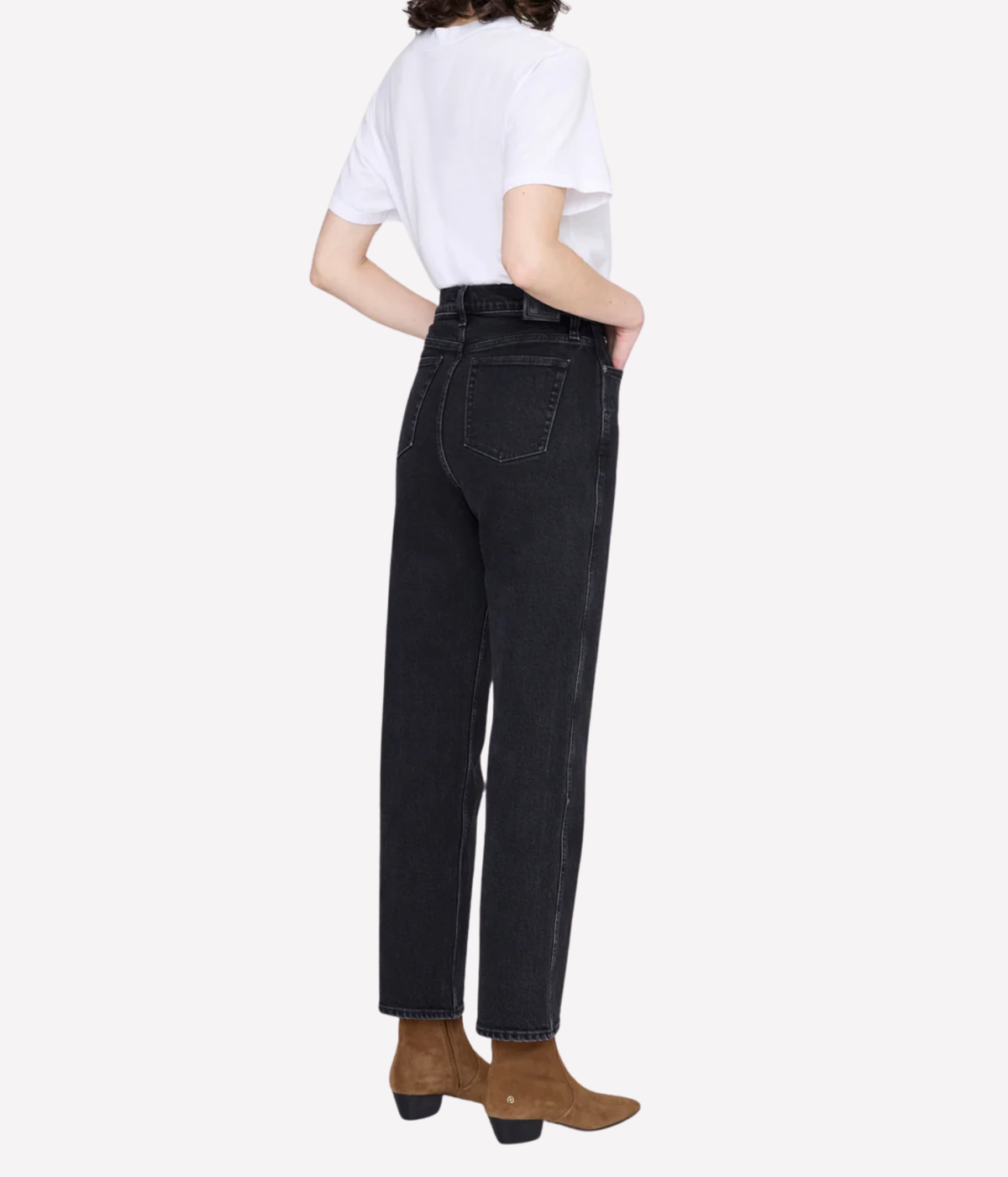 A model shown from the back wearing high-waisted black denim jeans, a white t-shirt, and brown ankle boots against a light gray background.