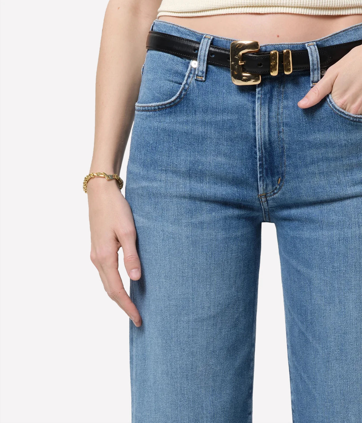 Close-up of a model wearing the Citizens Of Humanity Annina 33" Jean in Stella, showing the high-rise waist, front pockets and a black leather belt with a gold buckle, worn with a gold bracelet