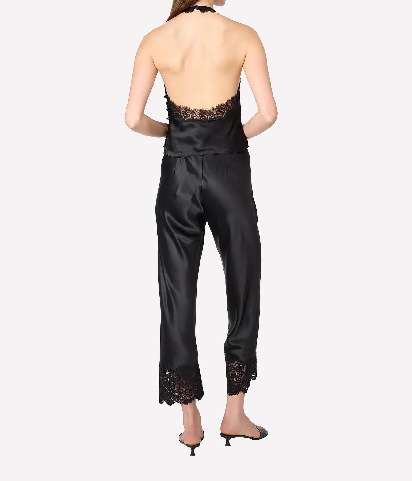 A woman shown from the back wearing a black satin halter with lace trim at the back neckline