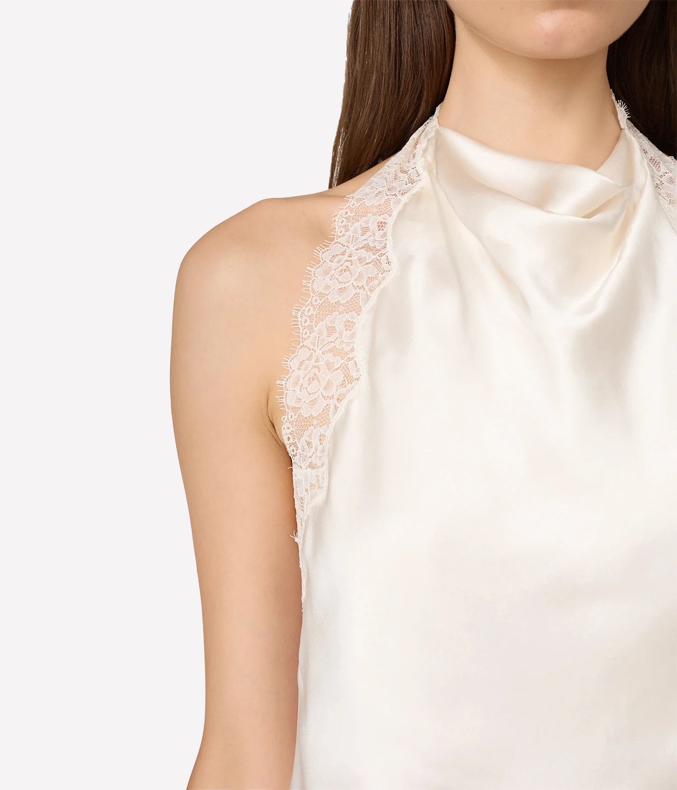 Close-up of a model wearing a cream satin halter top with white floral lace trim along the shoulders