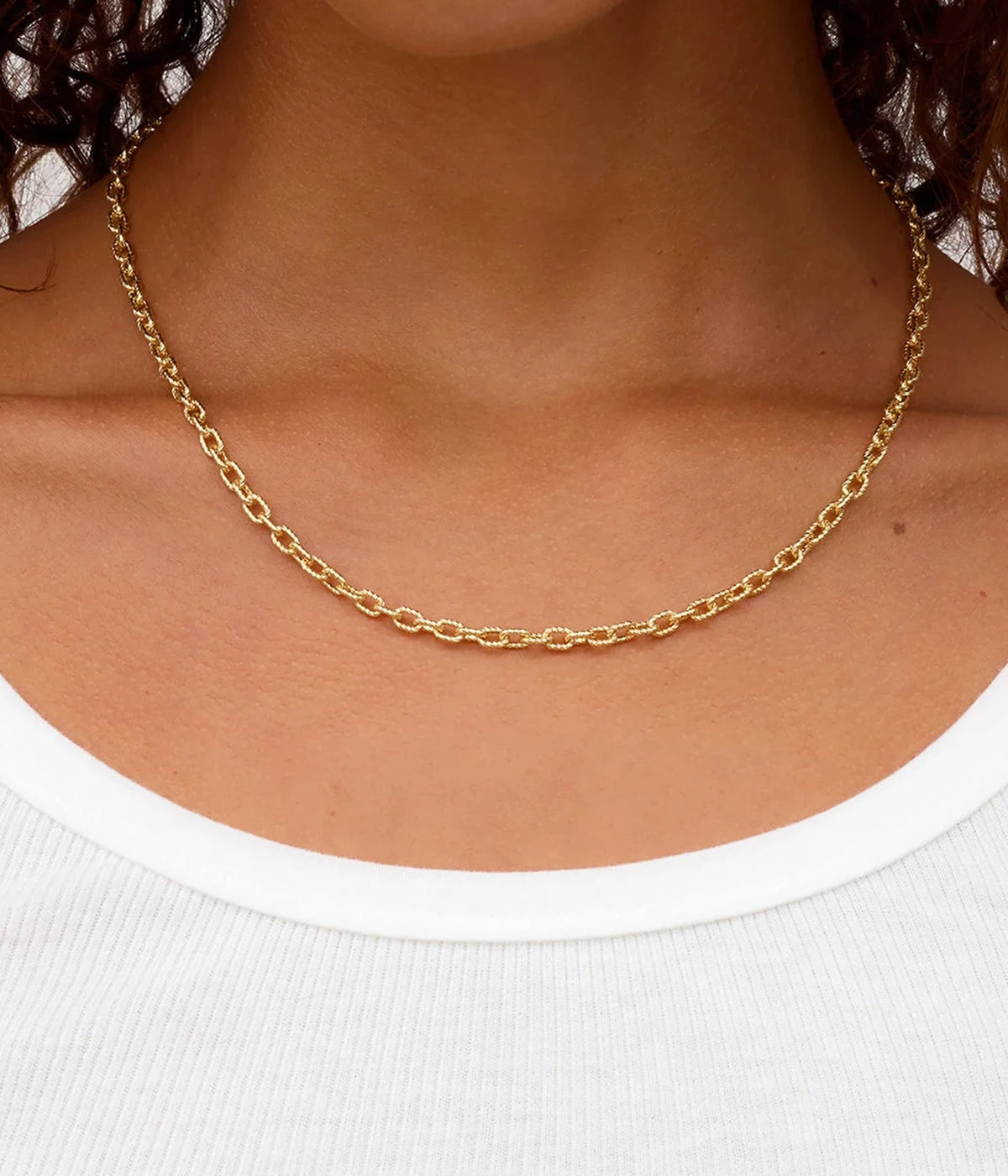 Close-up of a model wearing the Gorjana Crew Mini Link Necklace in Yellow Gold with a white scoop-neck tank top, showing where the chain sits on the collarbone