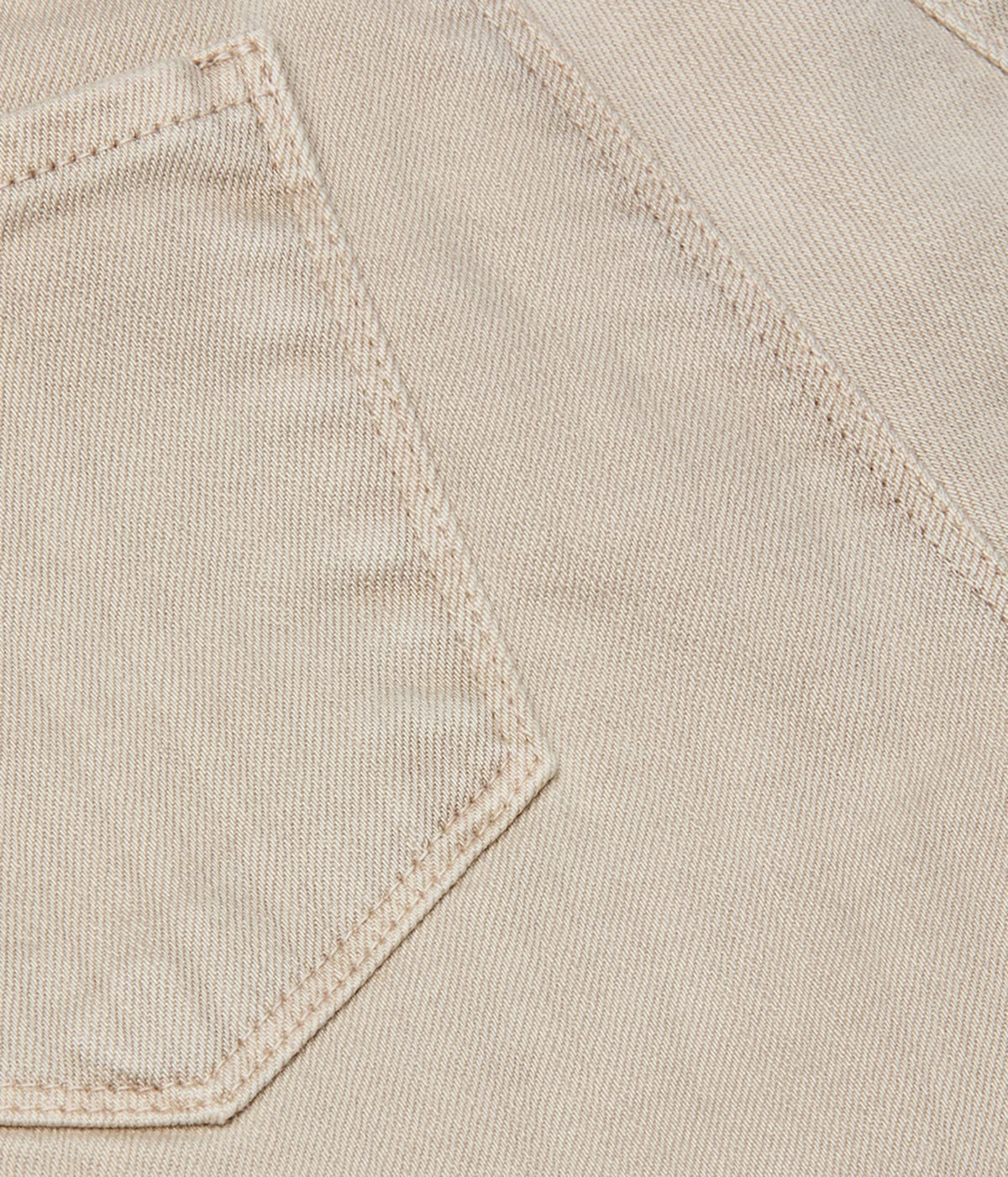 Close-up detail of a the L'AGENCE Selma Bootcut Jean in Biscuit. Showcasing its beige fabric garment showing a stitched pocket and fine woven texture.