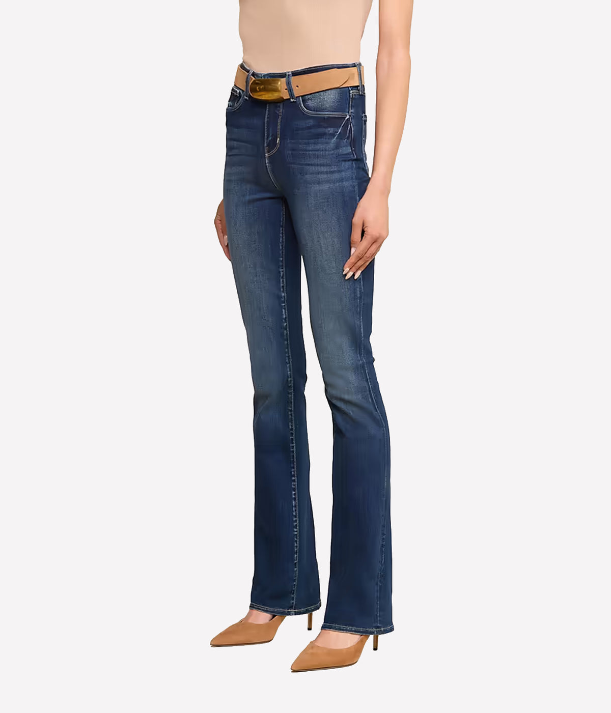 A model wearing a pair of dark blue jeans with a tan leather belt, paired with beige heels, shown from the waist down.