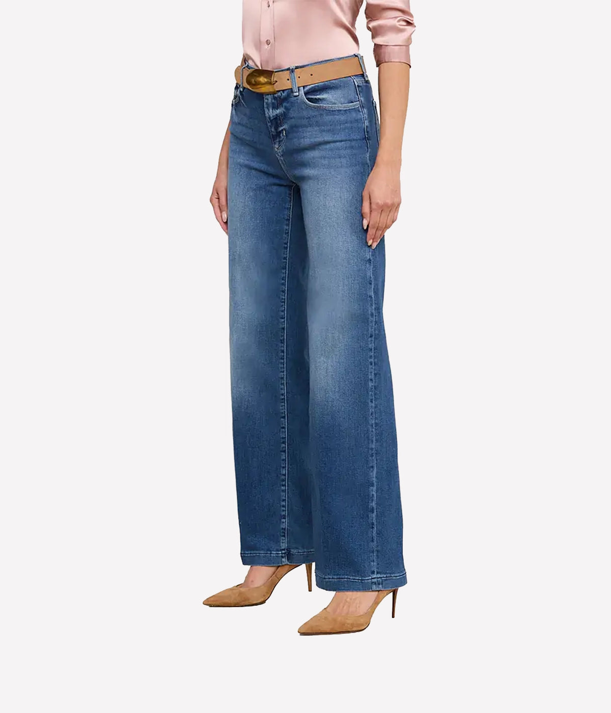 A model wearing a the L'AGENCE Scottie Wide-Leg Denim Jean in Cambridge with a tan belt, paired with a pink satin blouse and beige pointed-toe heels, shown from the waist down.