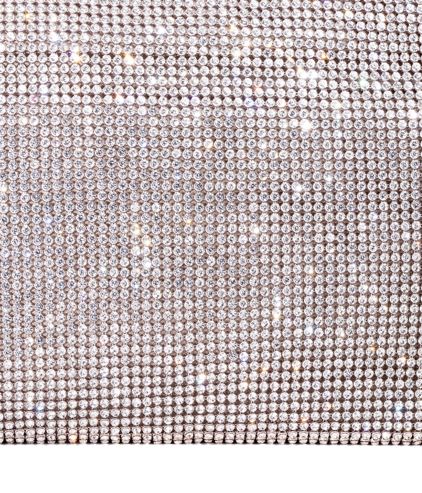 A close-up of a rhinestone-covered surface with dense rows of clear faceted stones in a silver-toned setting, creating a sparkling light-reflective texture against a white background.
