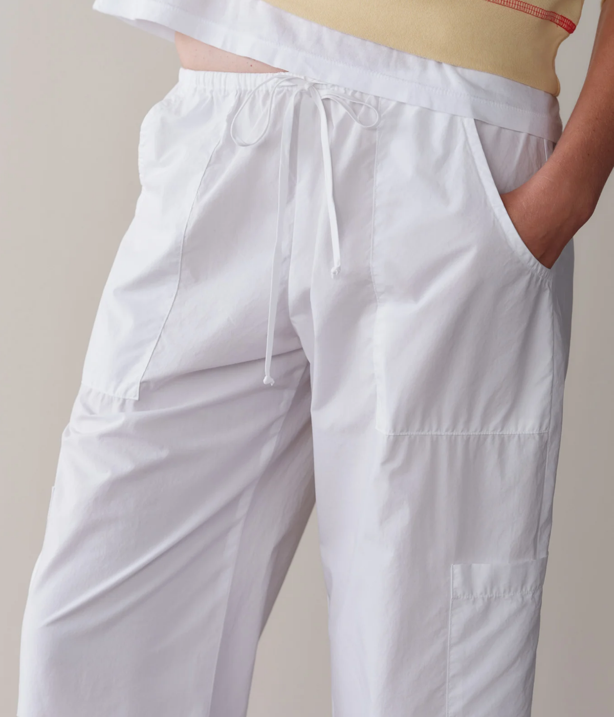 Close-up of the DONNI. The Pop Drawstring Cargo Pant in Powder showing the tie drawstring, elastic waistband, slant pocket and panelled patch pockets