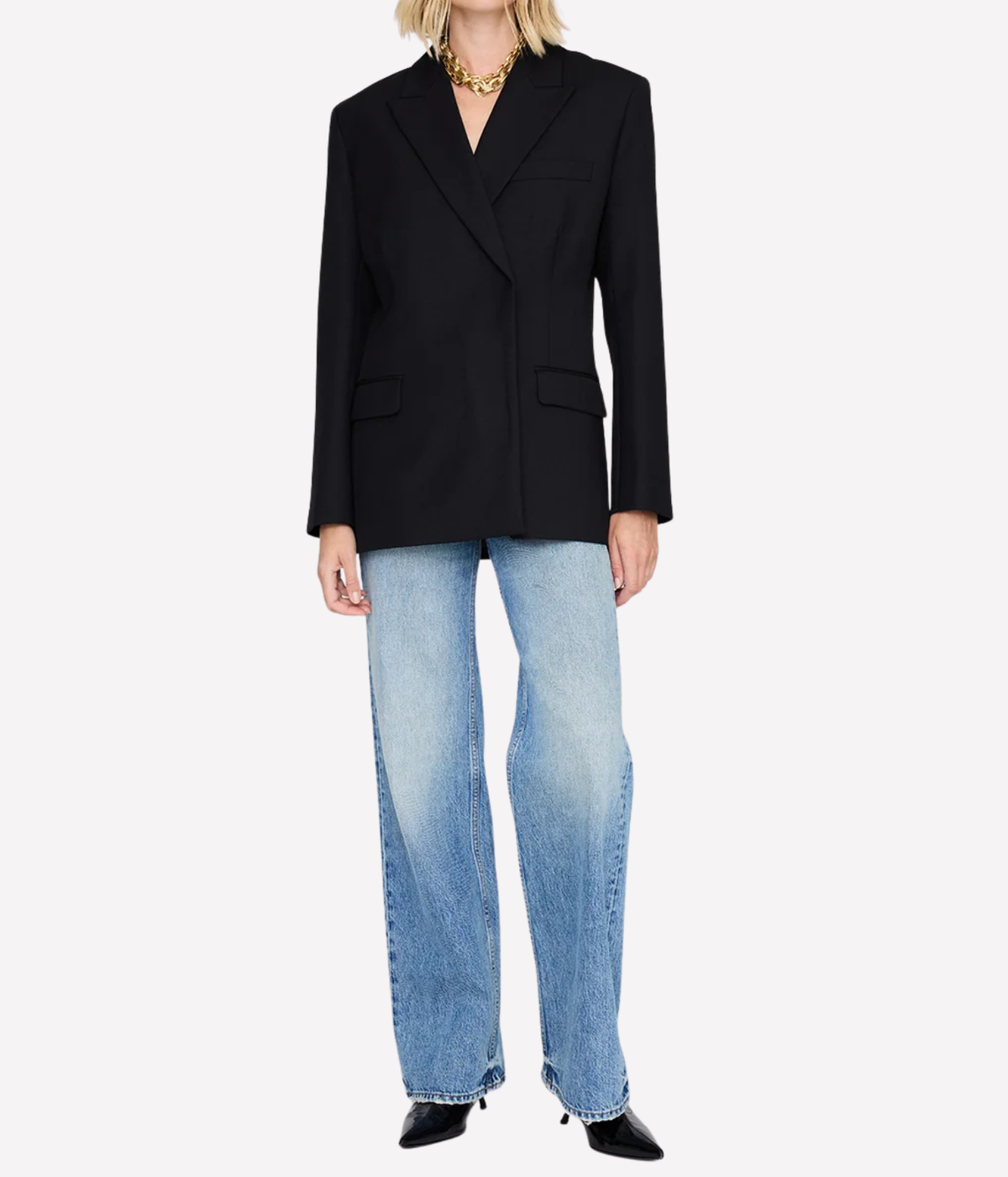 Model wearing the Anine Bing Aretha Blazer in Black buttoned over light-wash wide-leg jeans with a gold chain necklace and black pointed heels