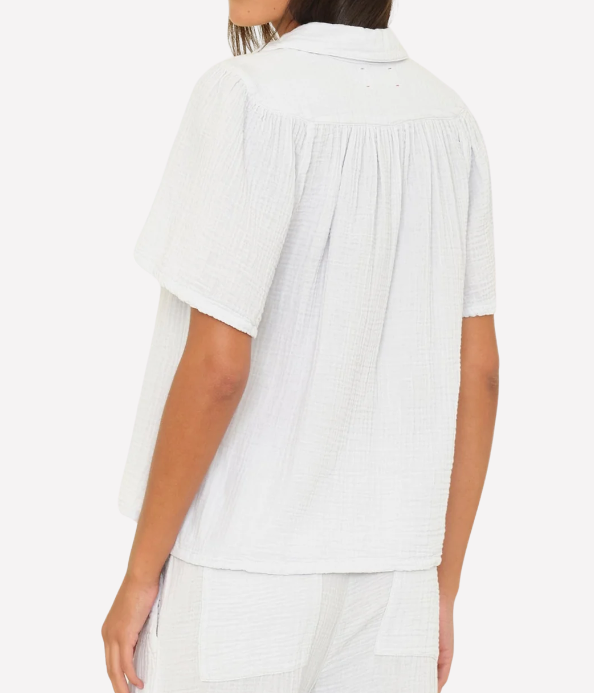 Back view of a model wearing the Xirena Rylee Top in Pale Sky with matching gauze pants, showing the shirring below the back yoke and short sleeves