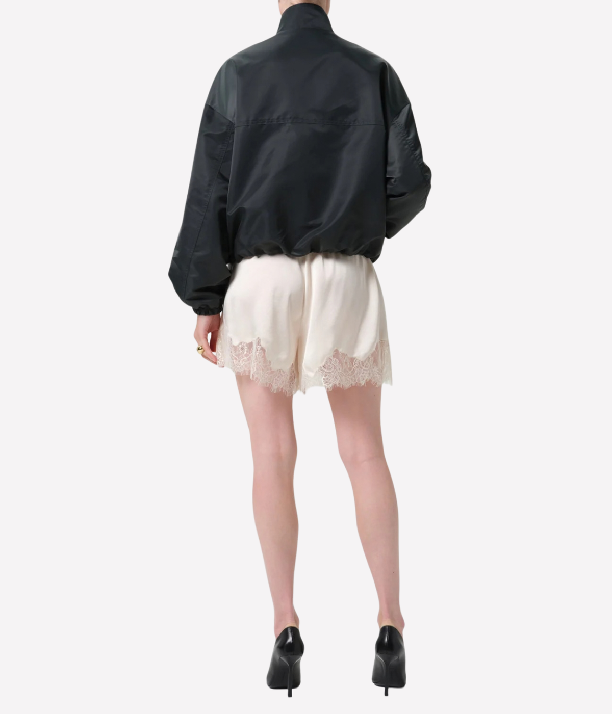 A model shown from the back wearing a black windbreaker jacket, cream lace-trimmed shorts - Lace Trimmed Tap Short in cream