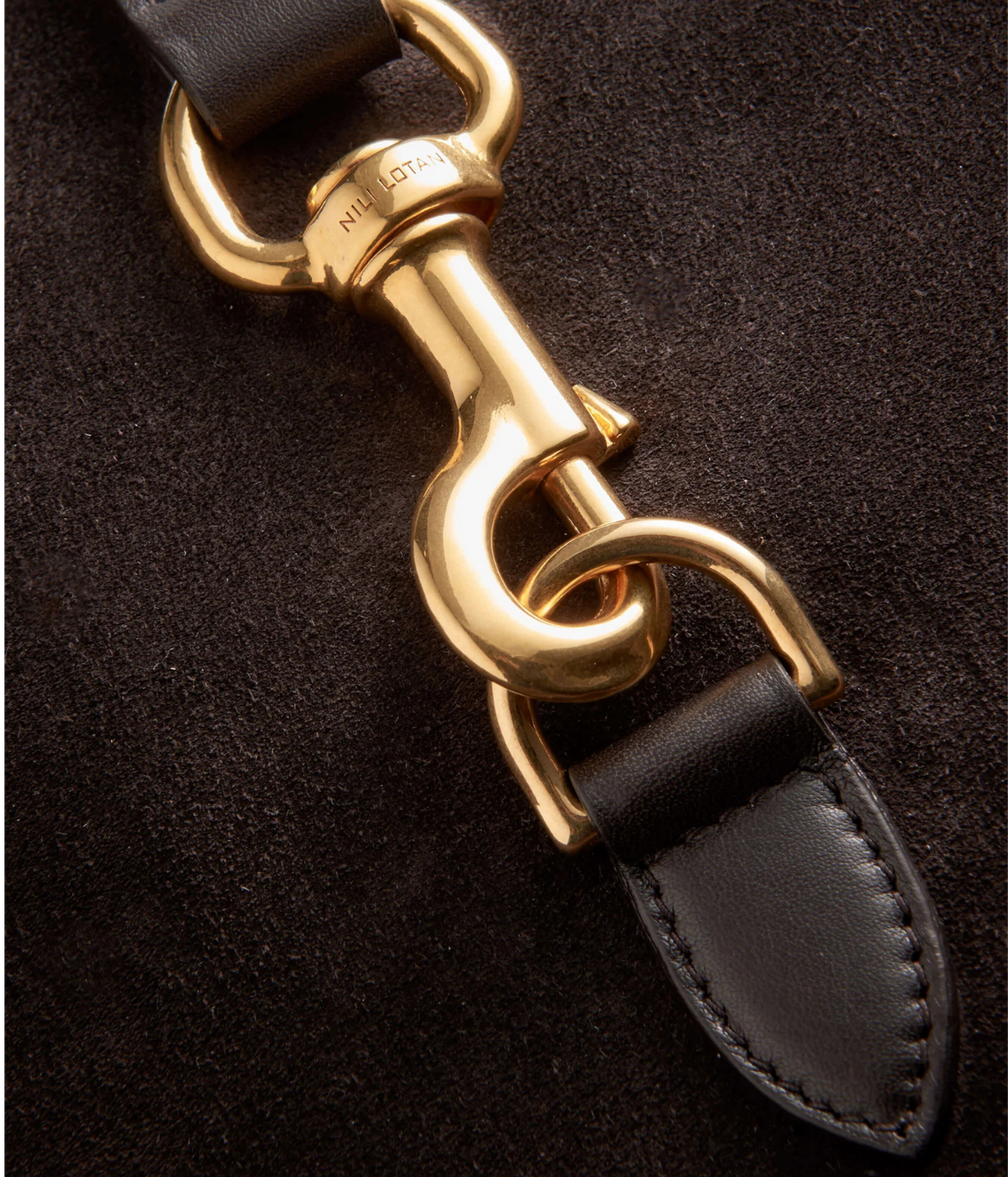 Close-up of a black leather strap with a polished gold-tone metal swivel clasp and D-rings, set against a dark textured background.