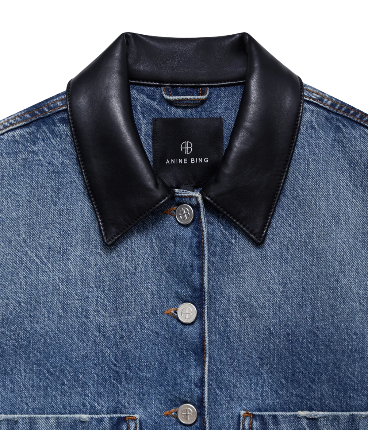 Close-up of a blue denim jacket with a contrasting black leather collar, featuring silver buttons and a visible Anine Bing brand label.