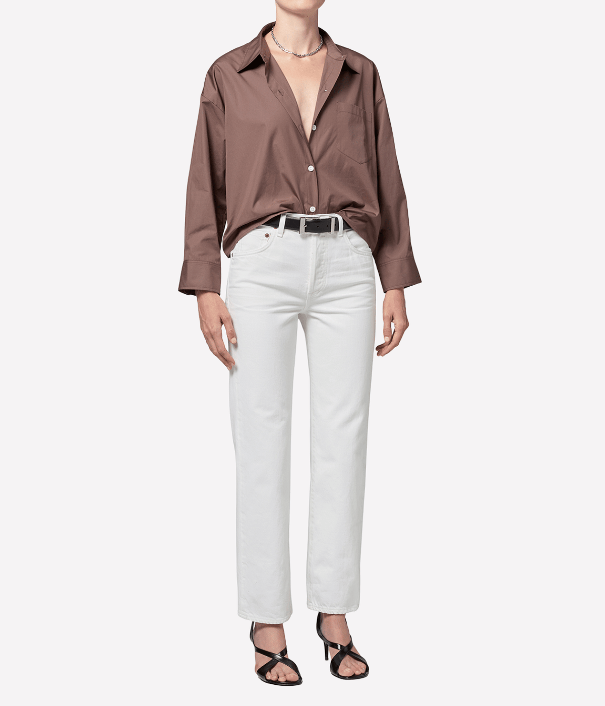 Model standing front-on in the Citizens Of Humanity 90s French High Rise Straight in vintage white, styled with an open-collar brown shirt, black belt and black strappy heels, showing the high rise and ankle-length hem