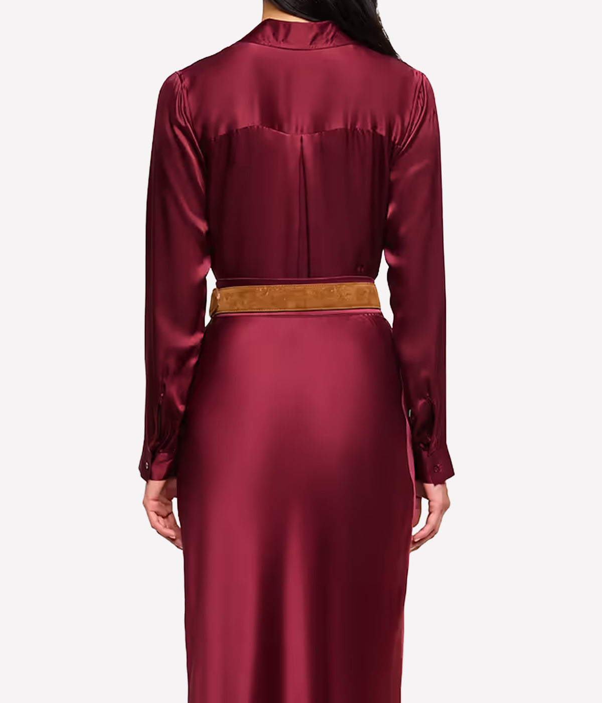 A model shown from the back wearing the L'AGENCE Tyler Silk Blouse in Merlot Red with a textured tan belt at the waist and matching silk skirt