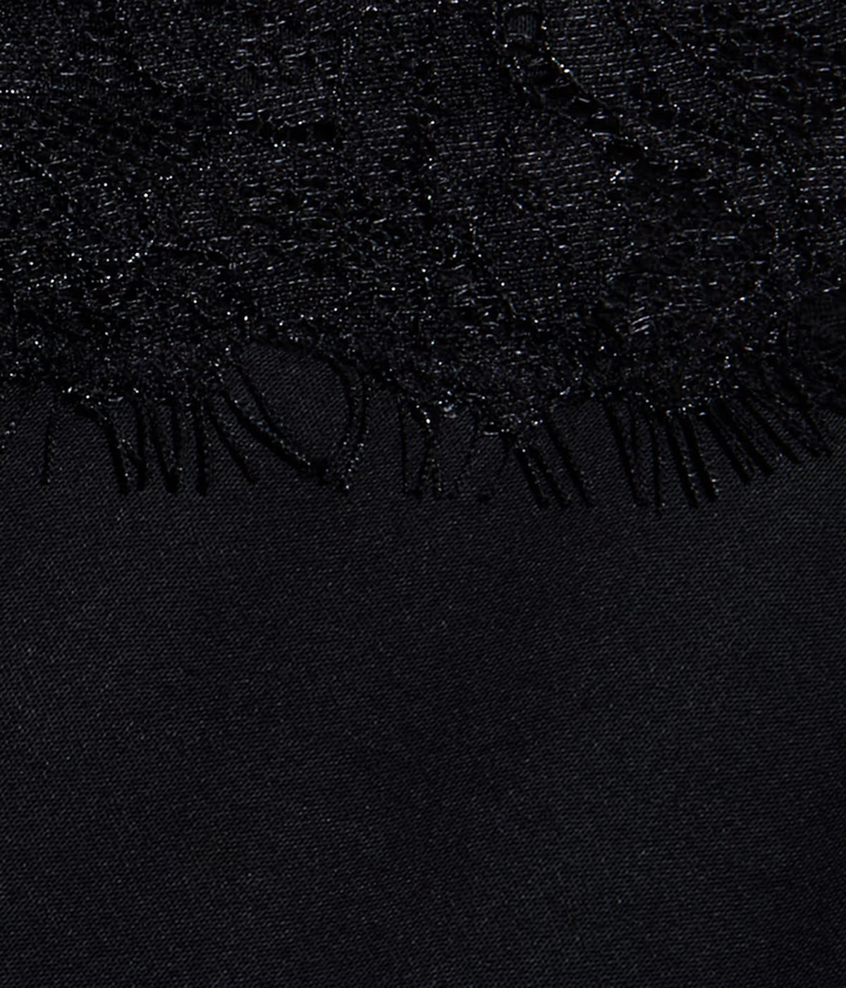 Close-up of the L'AGENCE Elka Satin Lace Camisole in Black. Showing its textured fabric with a lace trim along the top edge and a smooth black fabric below.