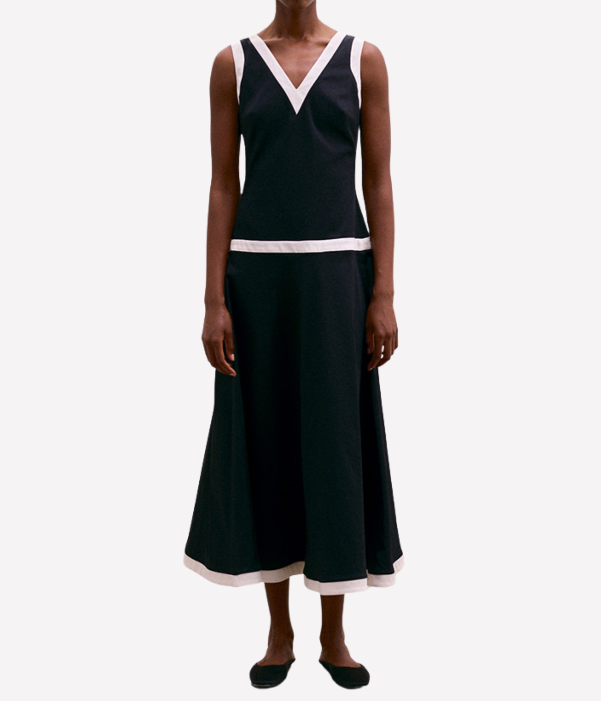 Black dress with white trim worn by a model on a white background