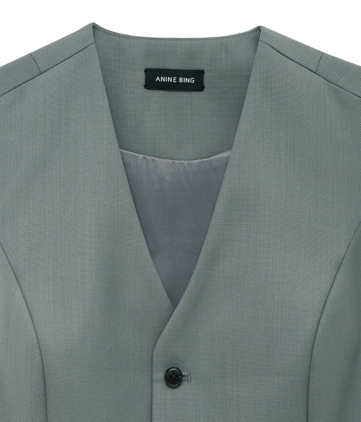 Close-up of the Anine Bing Mario Vest in Sage showing the V-neckline, brand label