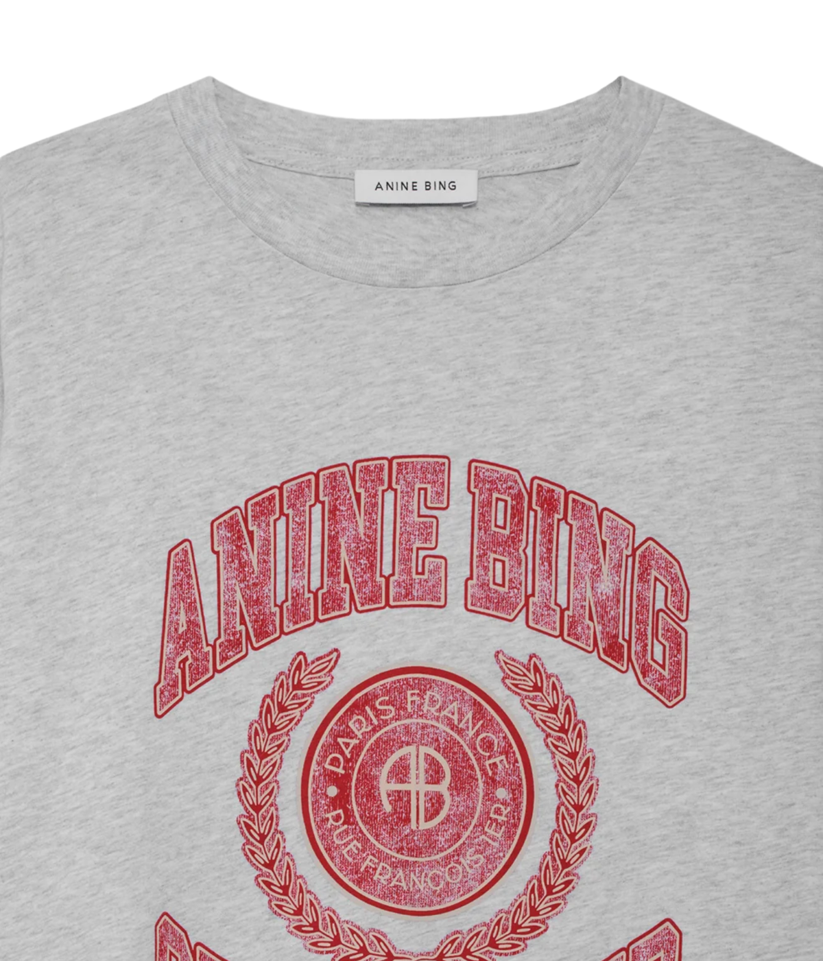 Close-up of a light heather gray t-shirt featuring a distressed red graphic print of the brand 'Anine Bing' with its circular emblem.