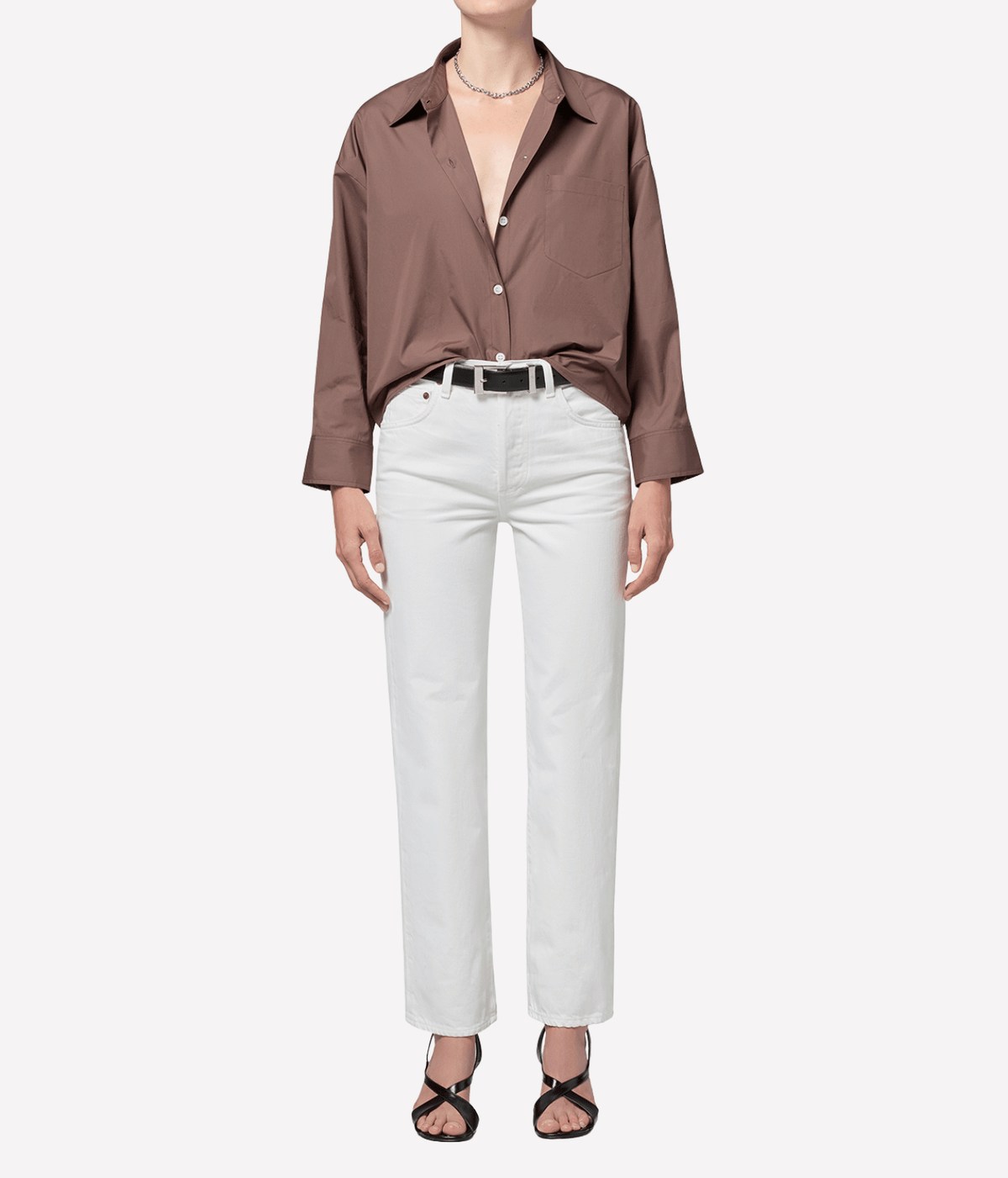 Front view of a model wearing the Citizens Of Humanity 90s French High Rise Straight in vintage white with a relaxed brown shirt, black belt, delicate necklace and black strappy heels, showing the full-length straight leg