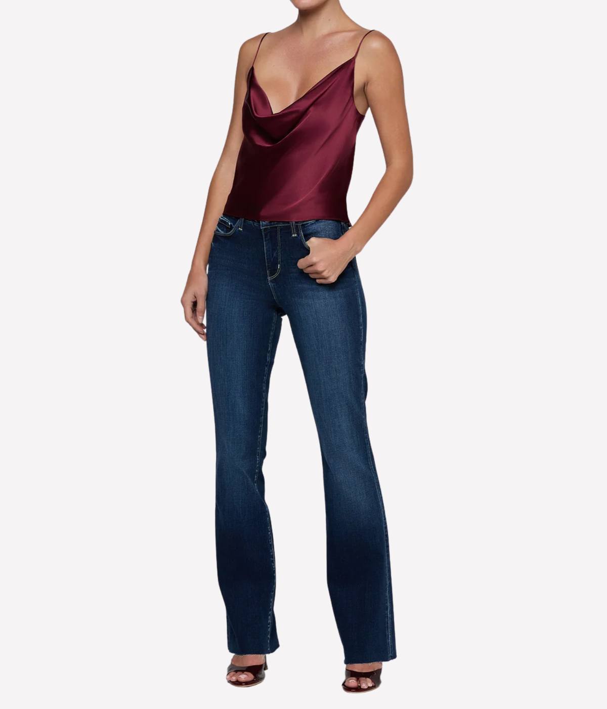 A model wearing a deep burgundy silk cowl-neck camisole top and dark blue straight-leg jeans.