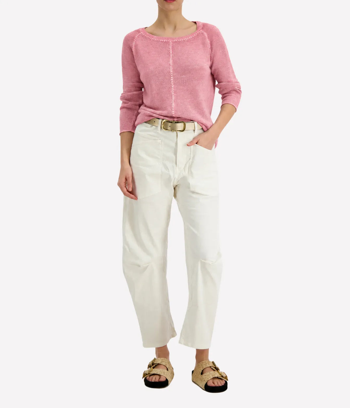 Model wearing the Avant Toi Maglia Pullover In Rose Skin tucked into cream barrel-leg trousers with a brown leather belt and dark sandals