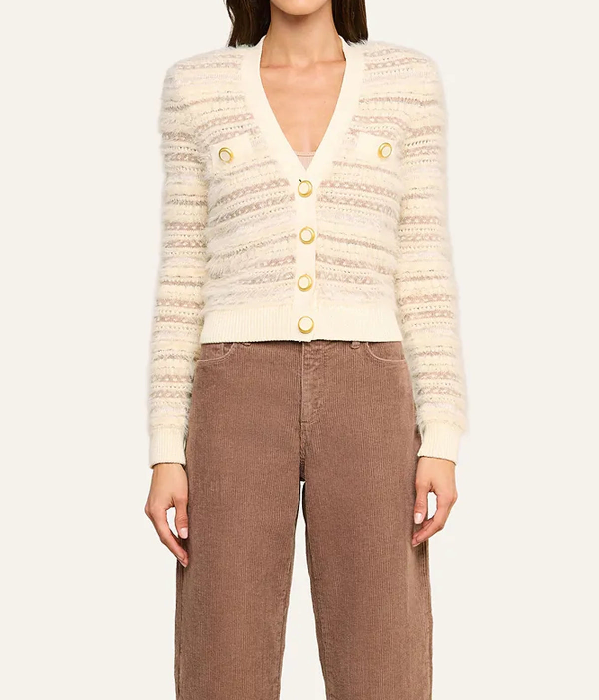 A model wearing a cream-coloured textured knit cardigan with gold buttons and brown corduroy trousers, front view.