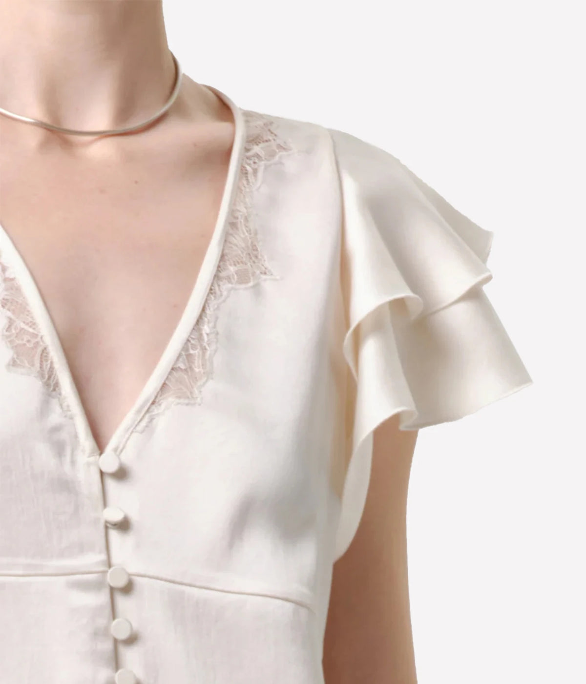 Close-up of the Citizens Of Humanity Lola Flutter Lace Sleeve Top in Cream, showing the embroidered lace along the V-neckline, covered buttons and double-layer flutter sleeve, worn with a gold choker necklace