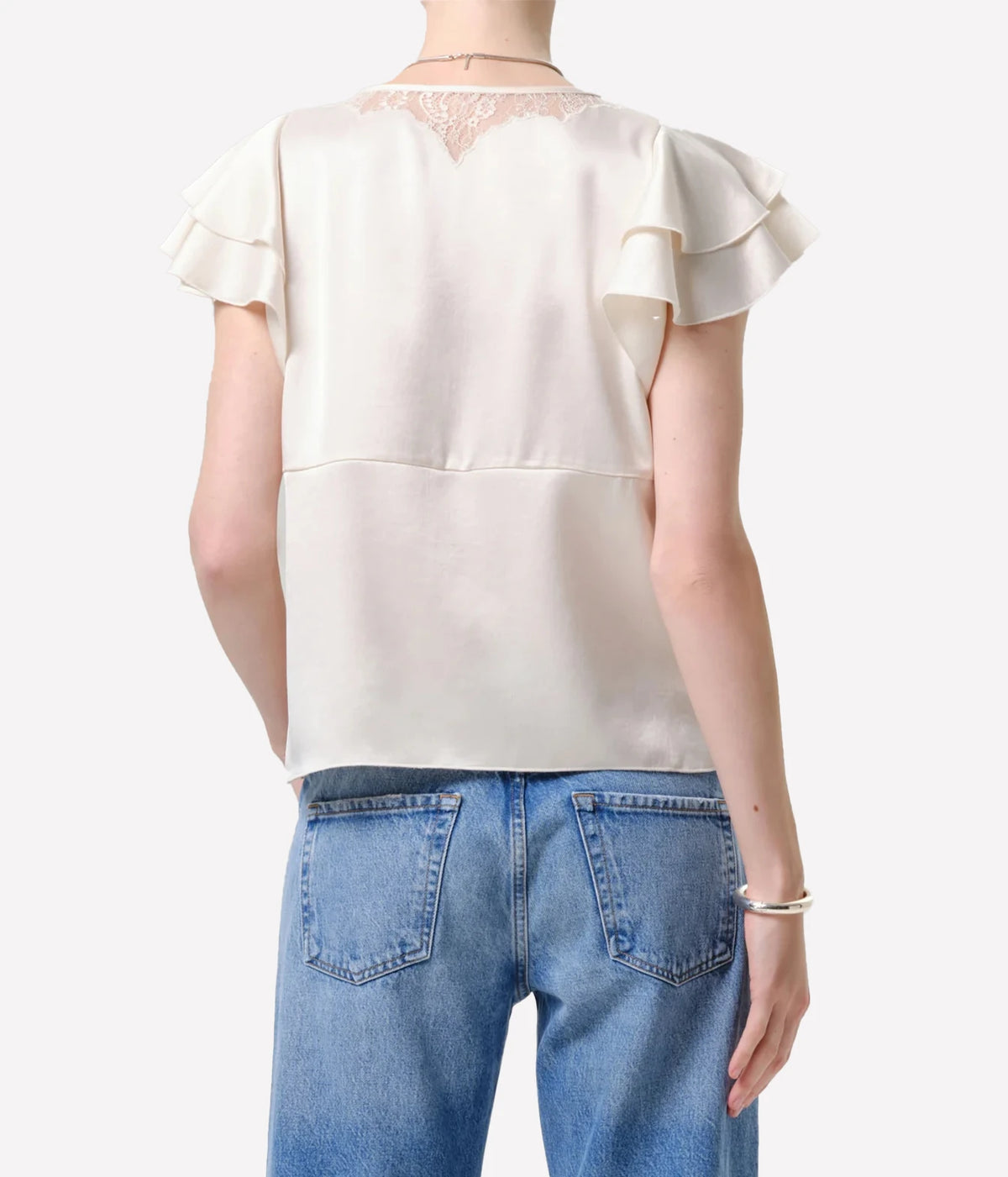 Back view of a model wearing the Citizens Of Humanity Lola Flutter Lace Sleeve Top in Cream with mid-wash jeans, showing the lace detail at the back neckline and flutter sleeves