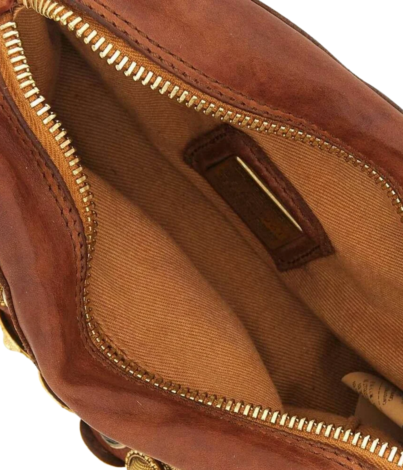 Close-up of the interior of a brown leather bag, showing a tan fabric lining, gold-tone zipper, and a small brown leather brand patch.