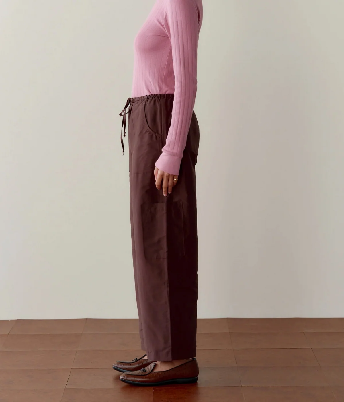Side profile of a model wearing the DONNI. The Silk Taffeta Cargo Pant in Espresso, showing the relaxed straight leg, side cargo pocket and full length