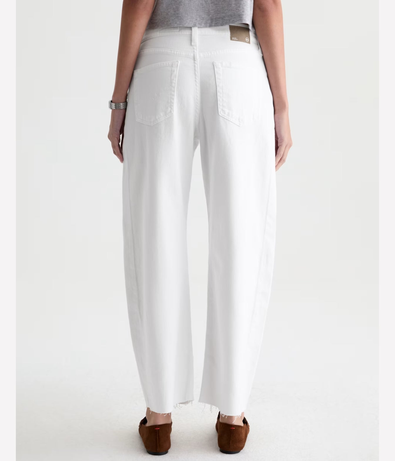 White wide-leg cropped jeans shown from the back on a model, paired with a gray top and brown flat shoes against a light gray studio background.