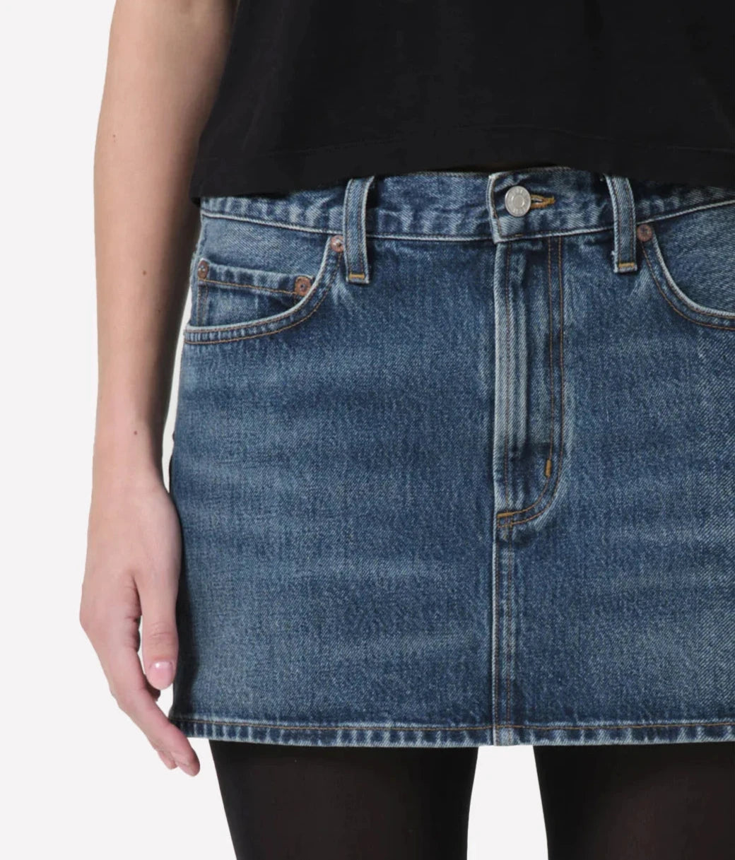Model wearing the Alek Mini Skirt paired with a casual tee and sneakers, showcasing its timeless style and flattering fit.