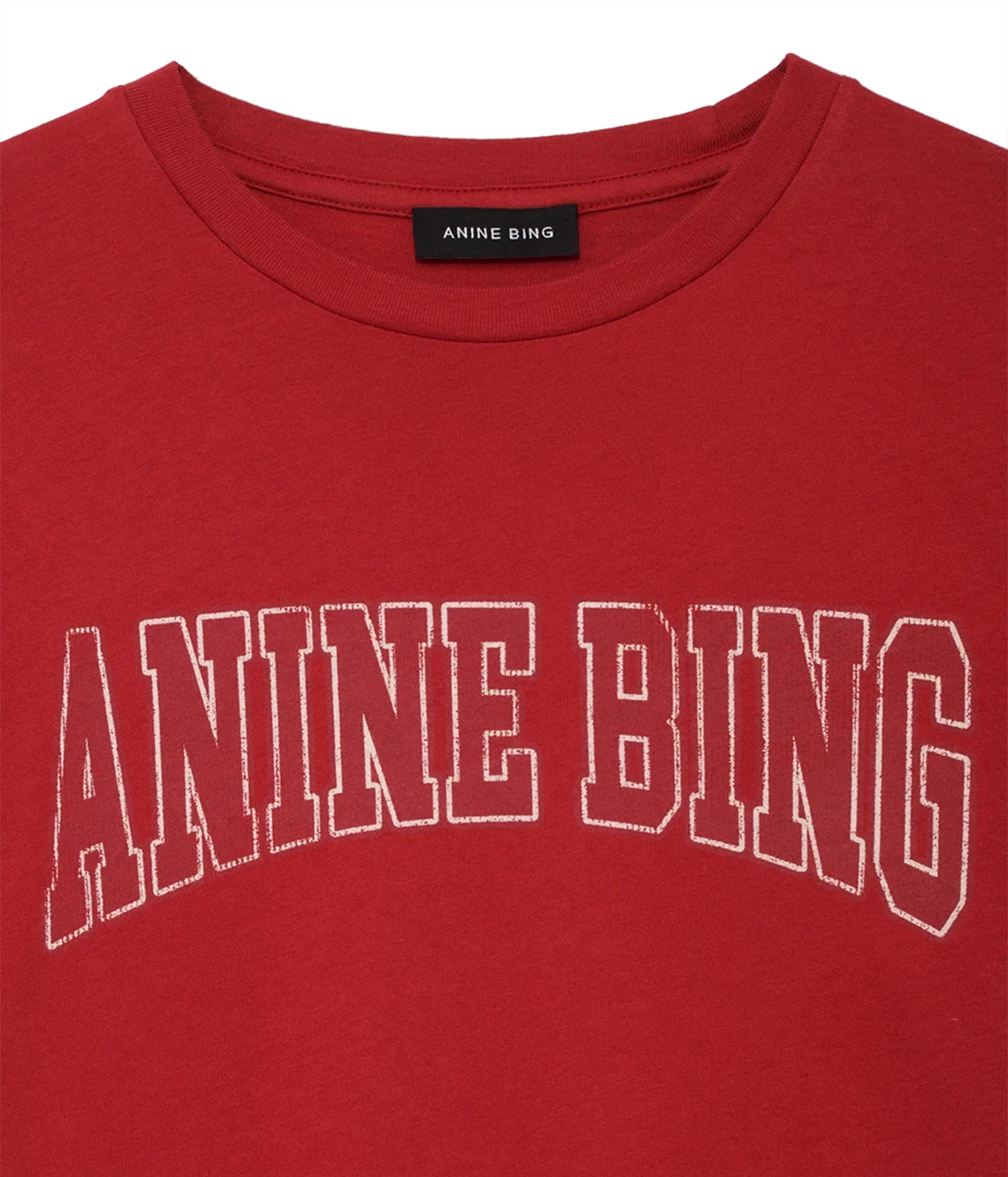 A close-up of a red crewneck t-shirt featuring the brand name 'ANINE BING' printed in white outline block letters across the chest. The black neck label also displays the brand name.