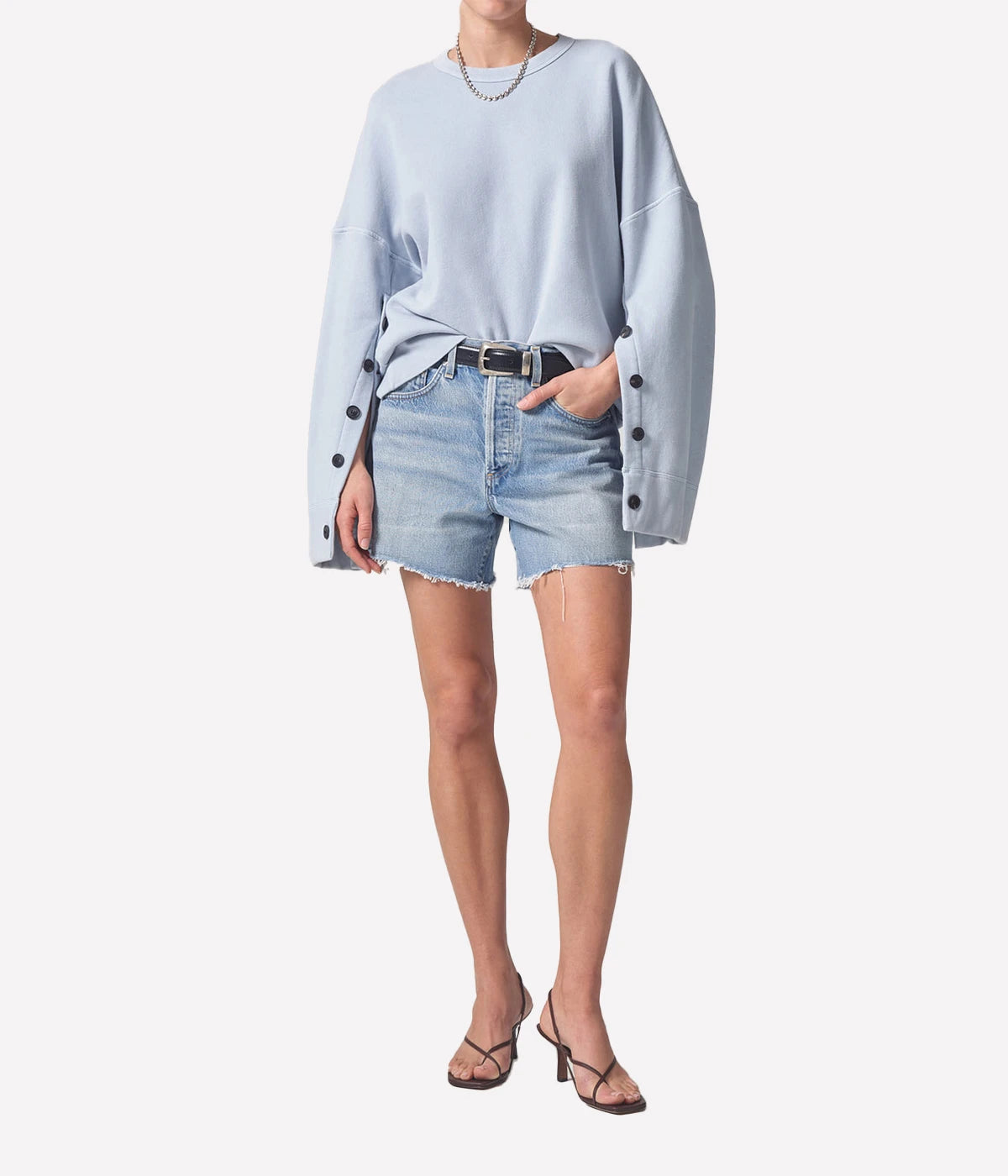 Relaxed-fit vintage-inspired denim shorts with distressed hems, styled with a linen button-up shirt and slides for an effortless summer look.