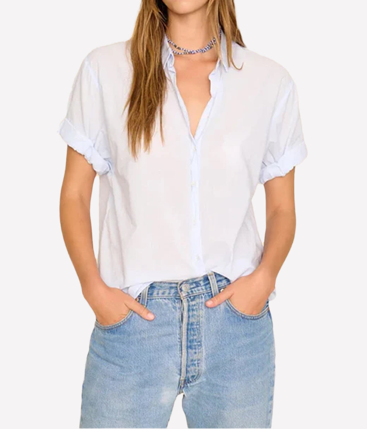 Model wearing the Xirena Channing Shirt in Skylight unbuttoned at the neck and tucked into light-wash jeans with a beaded choker and rolled sleeves