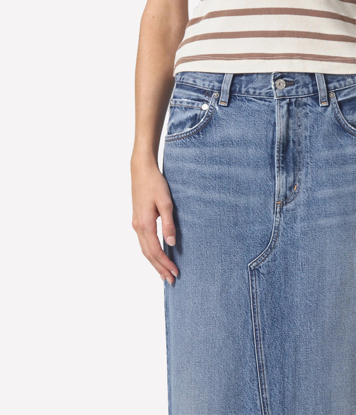 Full-length denim skirt with a raw hem and back slit detail, styled with a white tee and blazer for a modern, polished look.