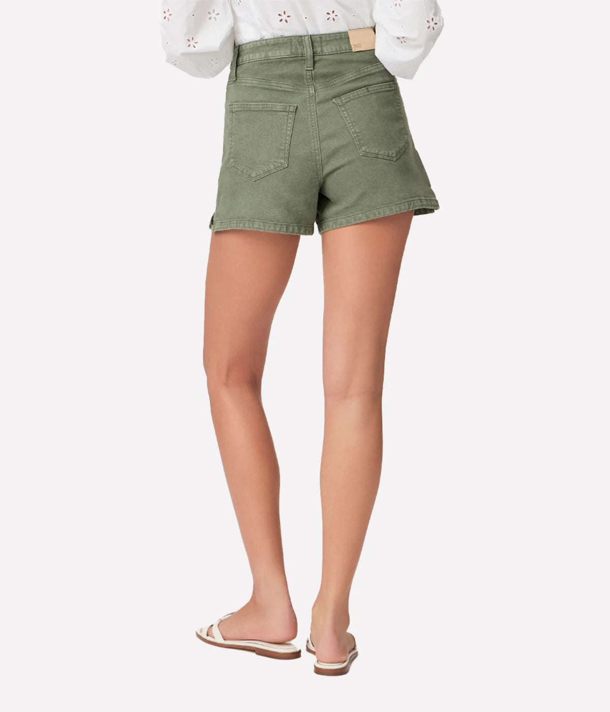 High-rise A-line shorts in vintage ivy green with silver hardware, styled with a white blouse and espadrilles for a relaxed yet chic look.