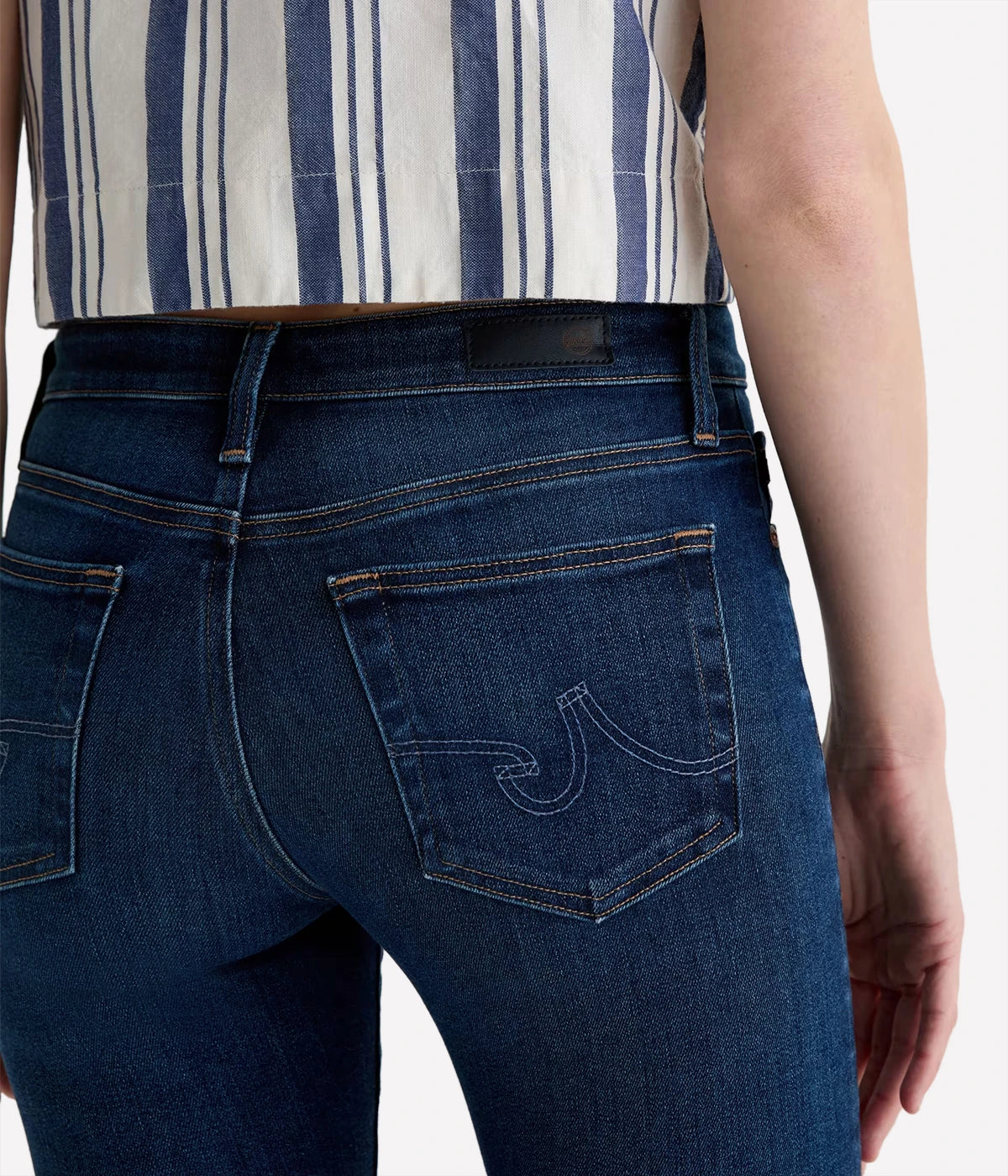 Person wearing blue jeans with a striped shirt underneath on a white background