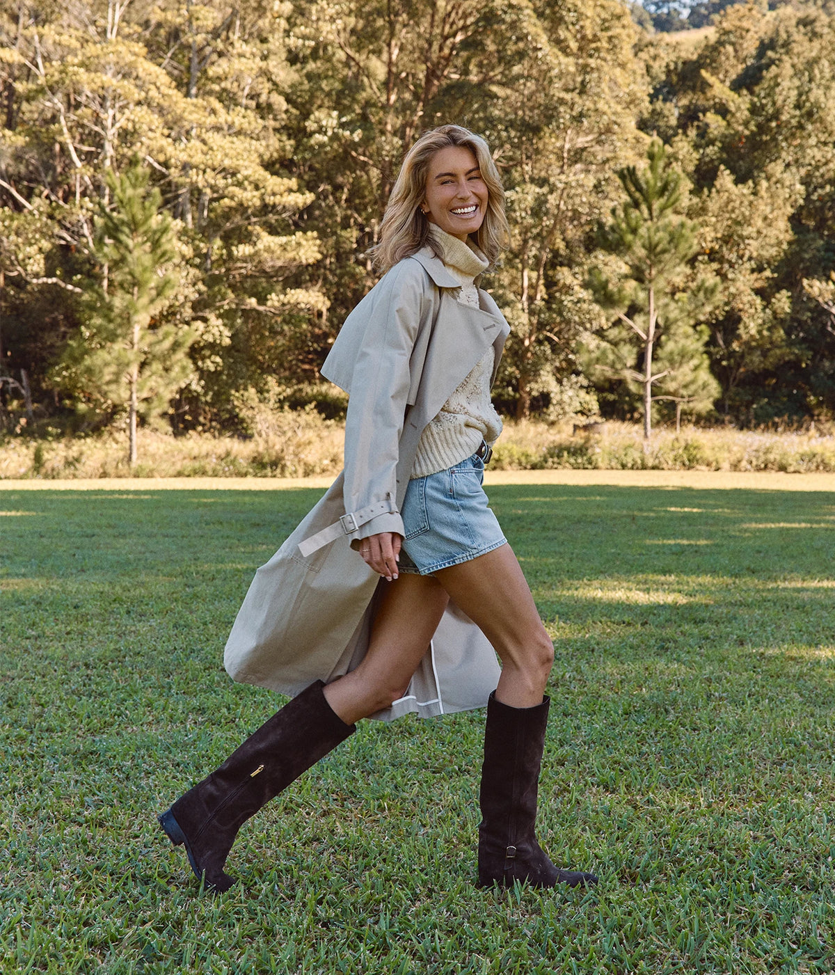 Avant Toi Hand Painted Leopard Jacquard Effect High Neck Pullover In Vaniglia, worn on model under an open trench coat with denim shorts and tall brown boots, walking across a lawn