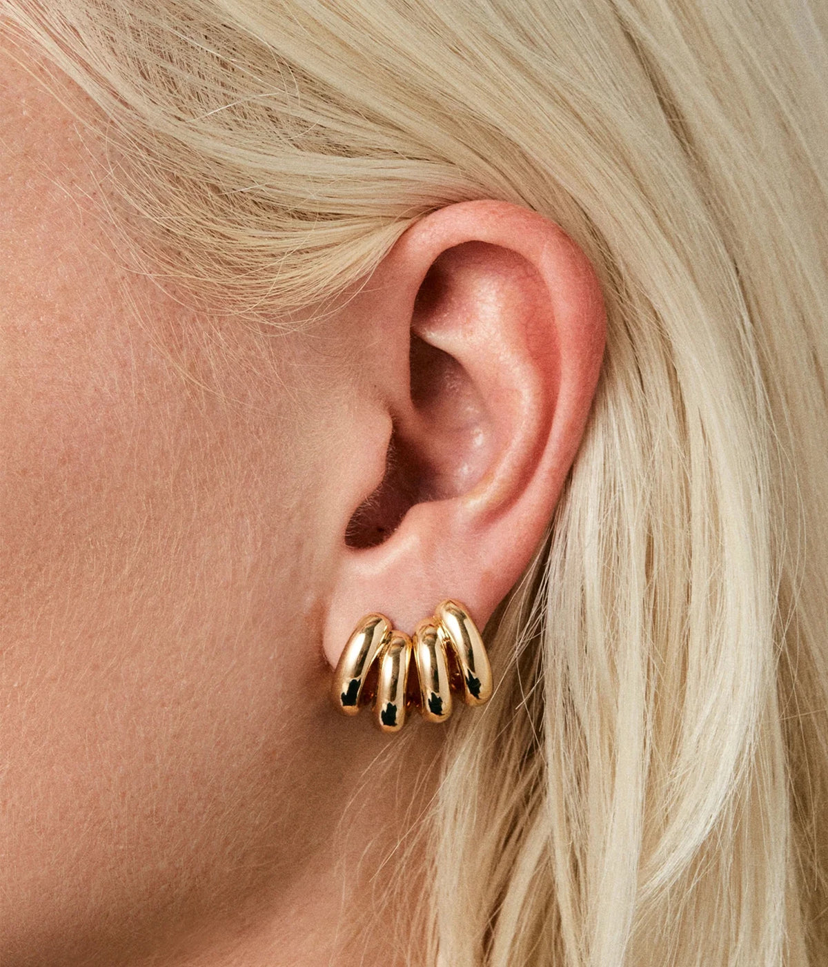 Close-up of a model with blonde hair tucked behind her ear wearing the Jenny Bird Mini Florence Earrings in Gold