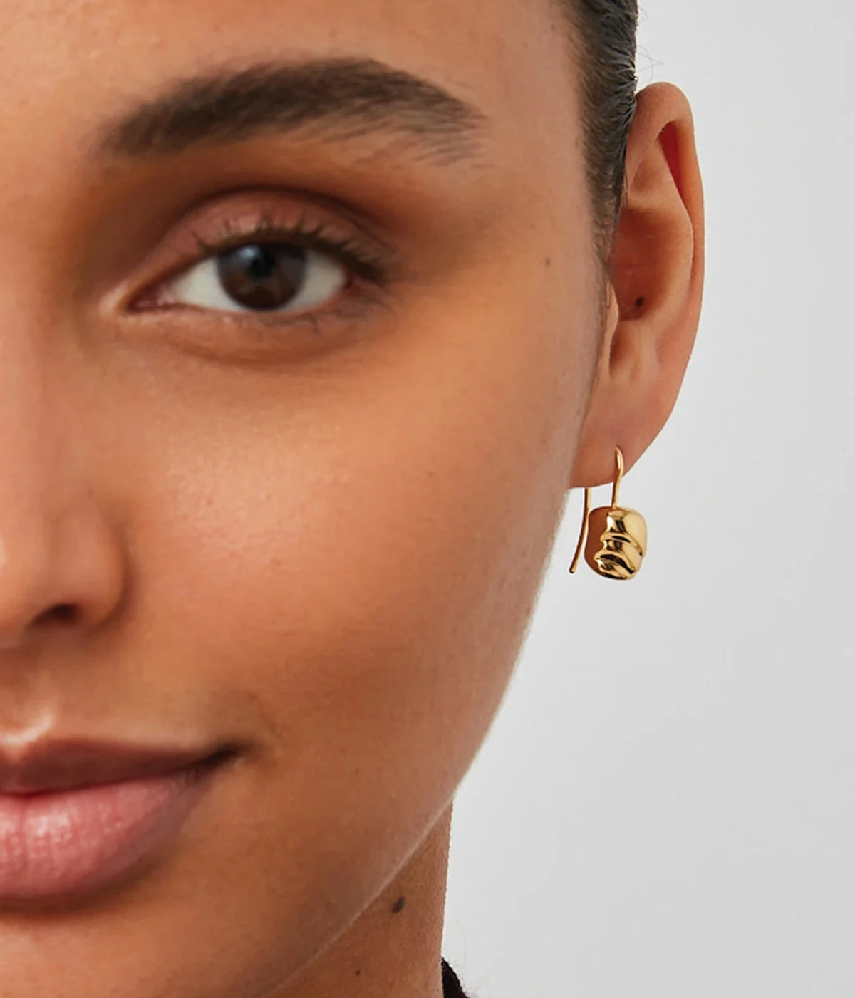 Close-up of a model facing forward with her hair pulled back wearing the Jenny Bird Rue Drop Earrings in Gold