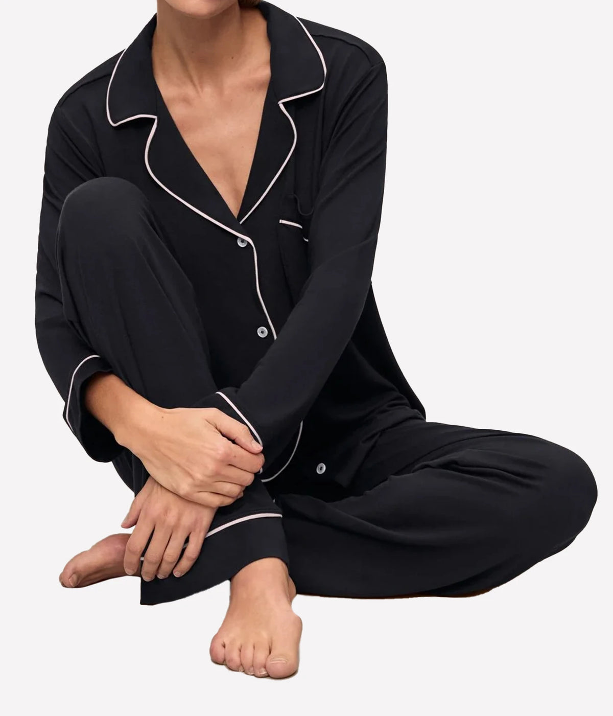 Model sitting cross-legged wearing the Eberjey Gisele Long Sleeve PJ Set in Black & Sorbet Pink, showing the piped cuffs and pant hems