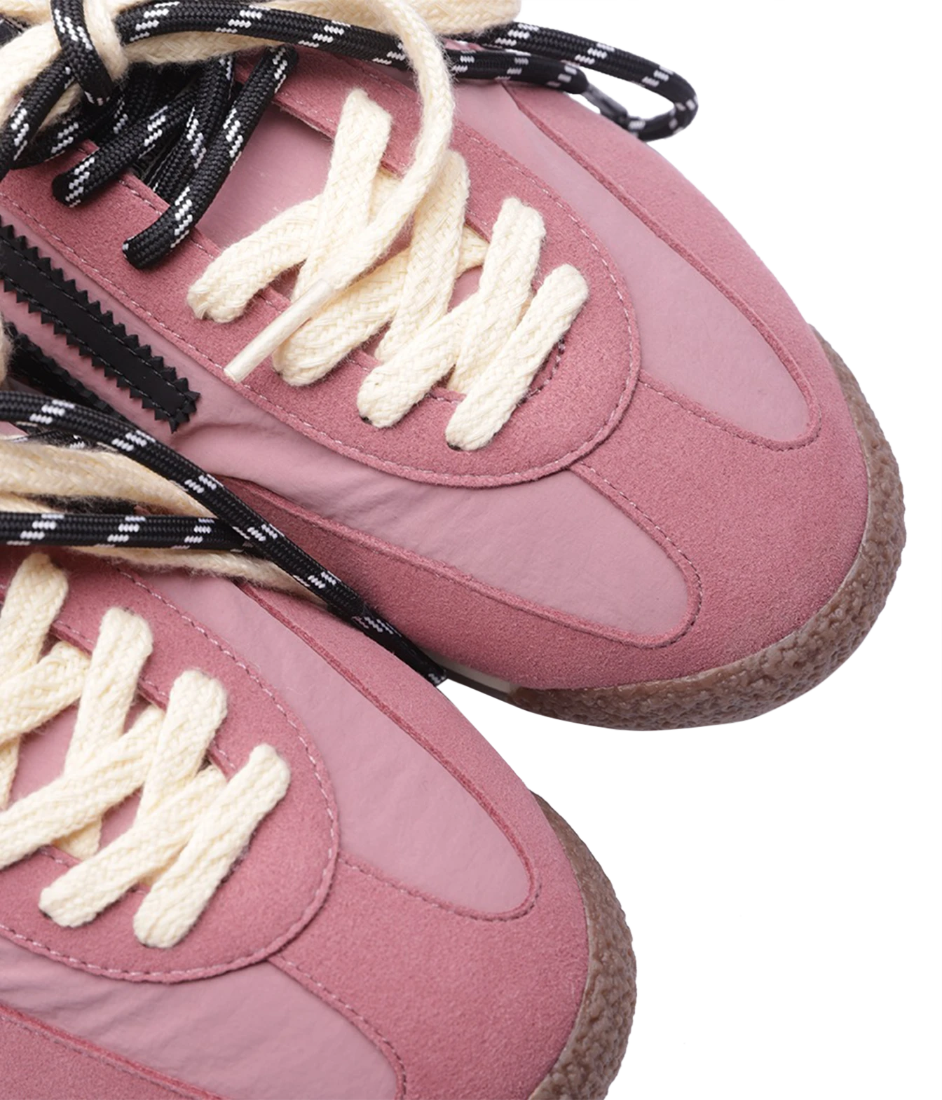 Close-up of a dusty pink sneaker with cream-colored laces and black-and-white patterned shoelaces, set against a plain white background.