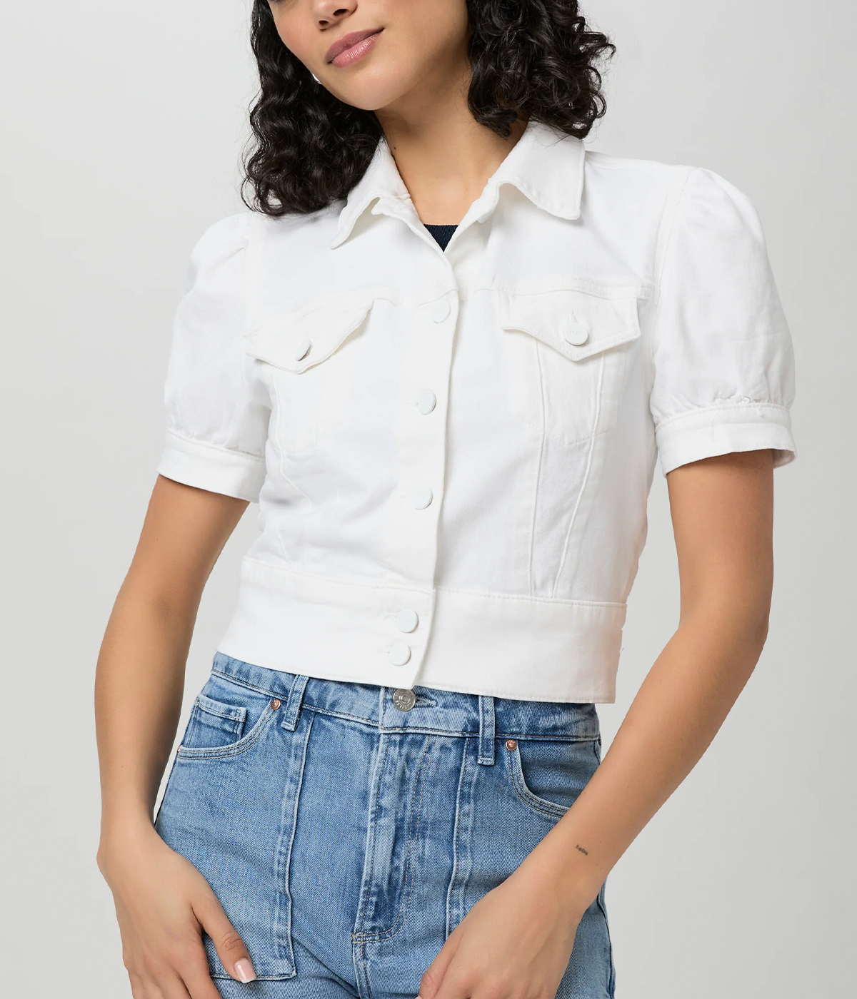 ALT text: White denim jacket with puff sleeves, cropped fit, and chest pockets.