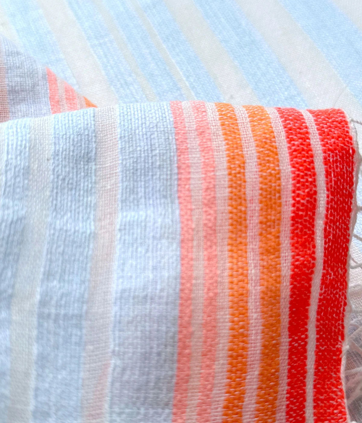 Airi Sky belted shorts featuring sky blue and cream stripes with vibrant orange accents, complete with an elastic waistband and front tie belt for a casual summer look.