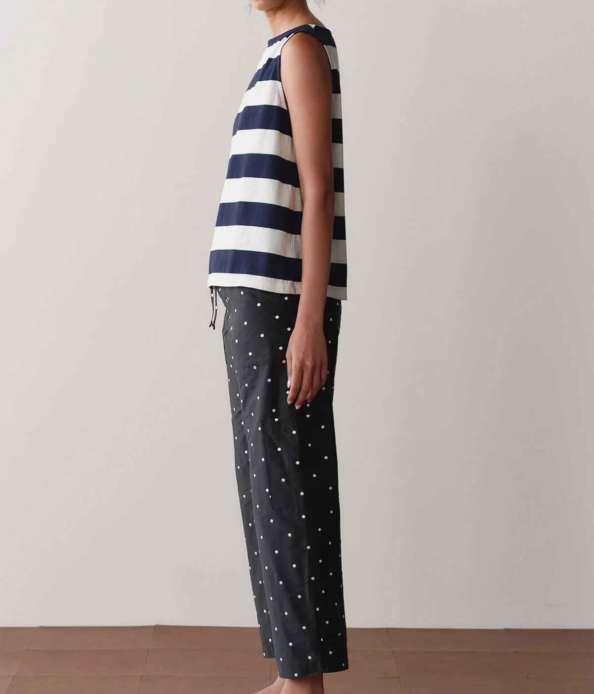 Model wearing black polka dot cargo pants with a striped tank top, shown from a side angle highlighting the side cargo pocket and straight-leg silhouette.