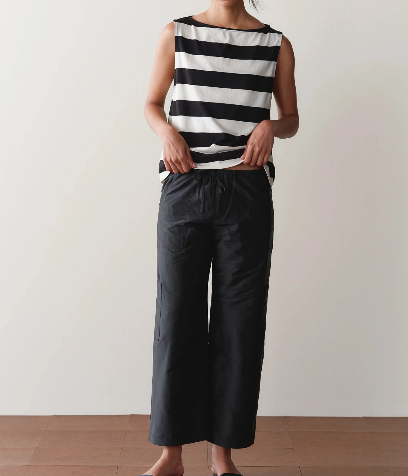 Model wearing black cargo pants with a striped tank top, side view showing the side cargo pocket.