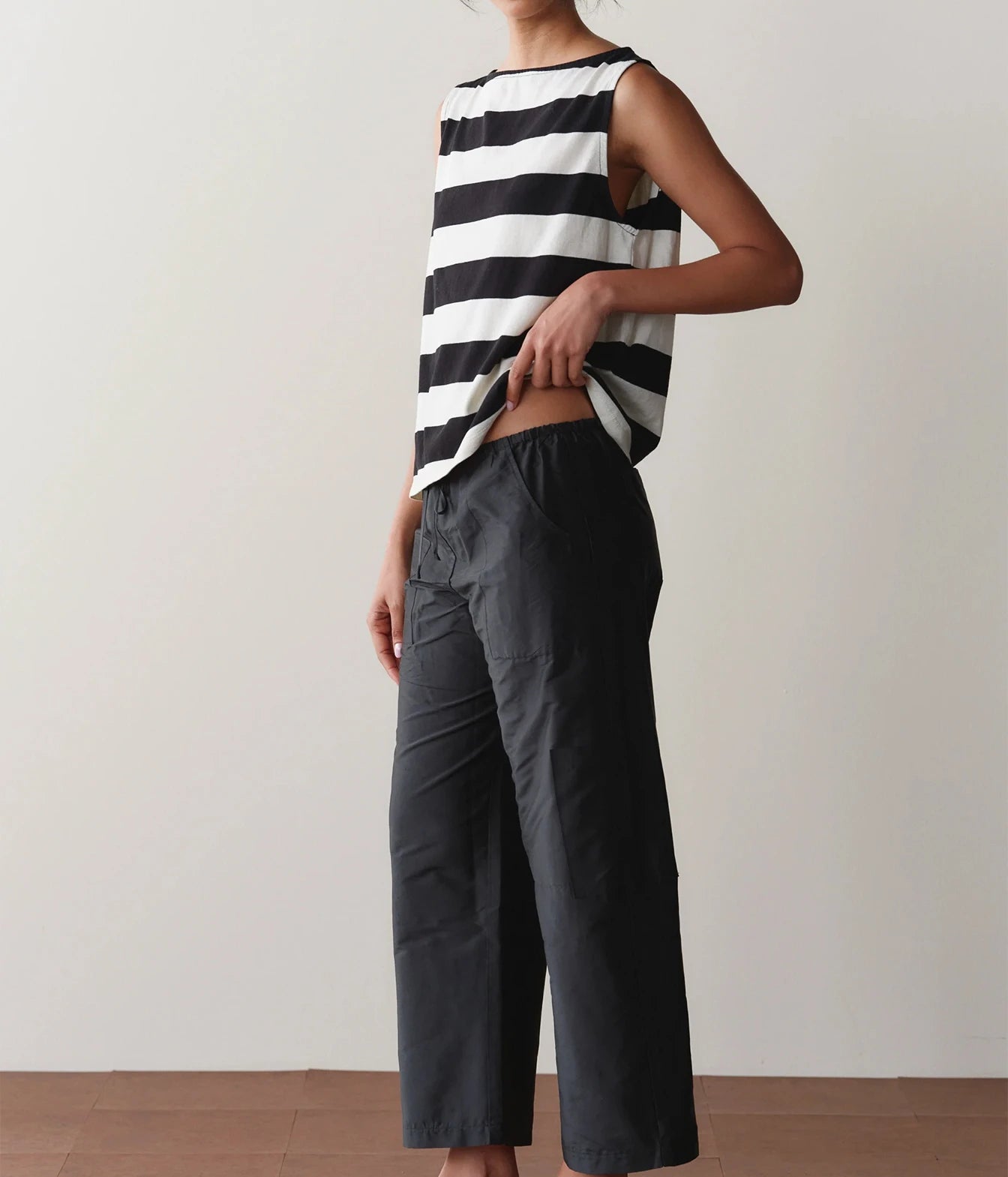 Model wearing black cargo pants, side view against a wall showing the relaxed leg silhouette.